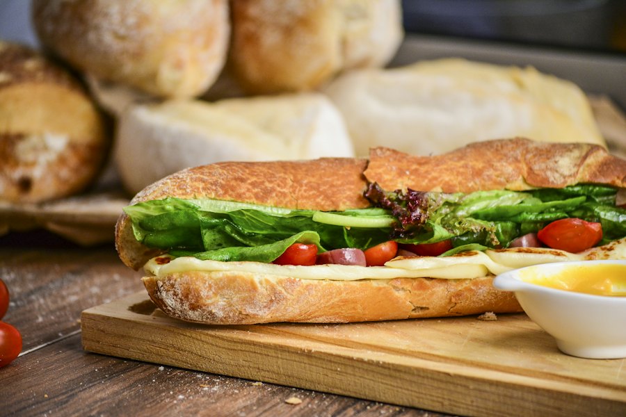 Belegd broodje met groenten op een houten plank